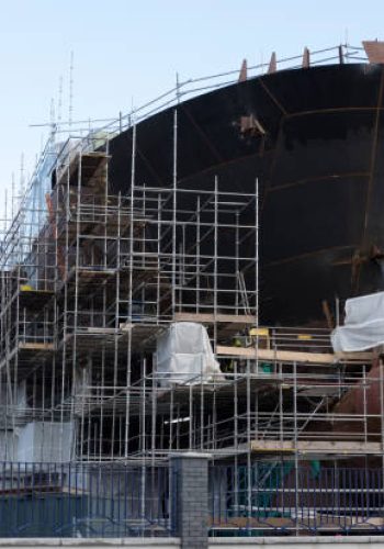 istockphoto-939107700-612×612 Shipbuilding progress scaffolding and crane large nautical vessel being built at dock port harbour harbour Glasgow traditional industry