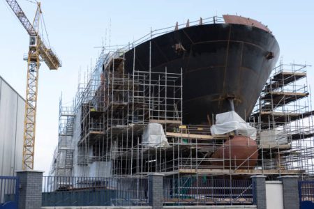 istockphoto-939107700-612×612 Shipbuilding progress scaffolding and crane large nautical vessel being built at dock port harbour harbour Glasgow traditional industry