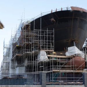 Shipbuilding progress scaffolding and crane large nautical vessel being built at dock port harbour harbour Glasgow traditional industry